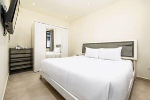 Une chambre avec un grand lit, une armoire et un miroir.