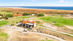 Un campo de golf con un club de campo, vista al océano y cielo despejado.