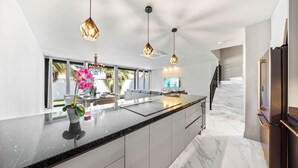 A modern kitchen with a large island, pendant lights, and a view to the outdoors.