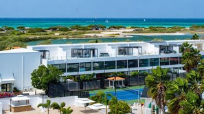A modern hotel with a rooftop pool, surrounded by lush greenery and a view of the ocean.