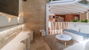 Uma sala de estar espaçosa com teto alto, paredes de pedra e um moderno conjunto de assentos.