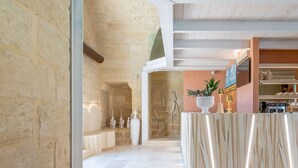 Eine geräumige Lobby mit Steinwand, einer Rezeption und einem Küchenbereich im Hintergrund.