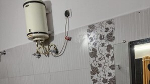 Een badkamer met toilet, wastafel en een aan de muur bevestigde boiler.