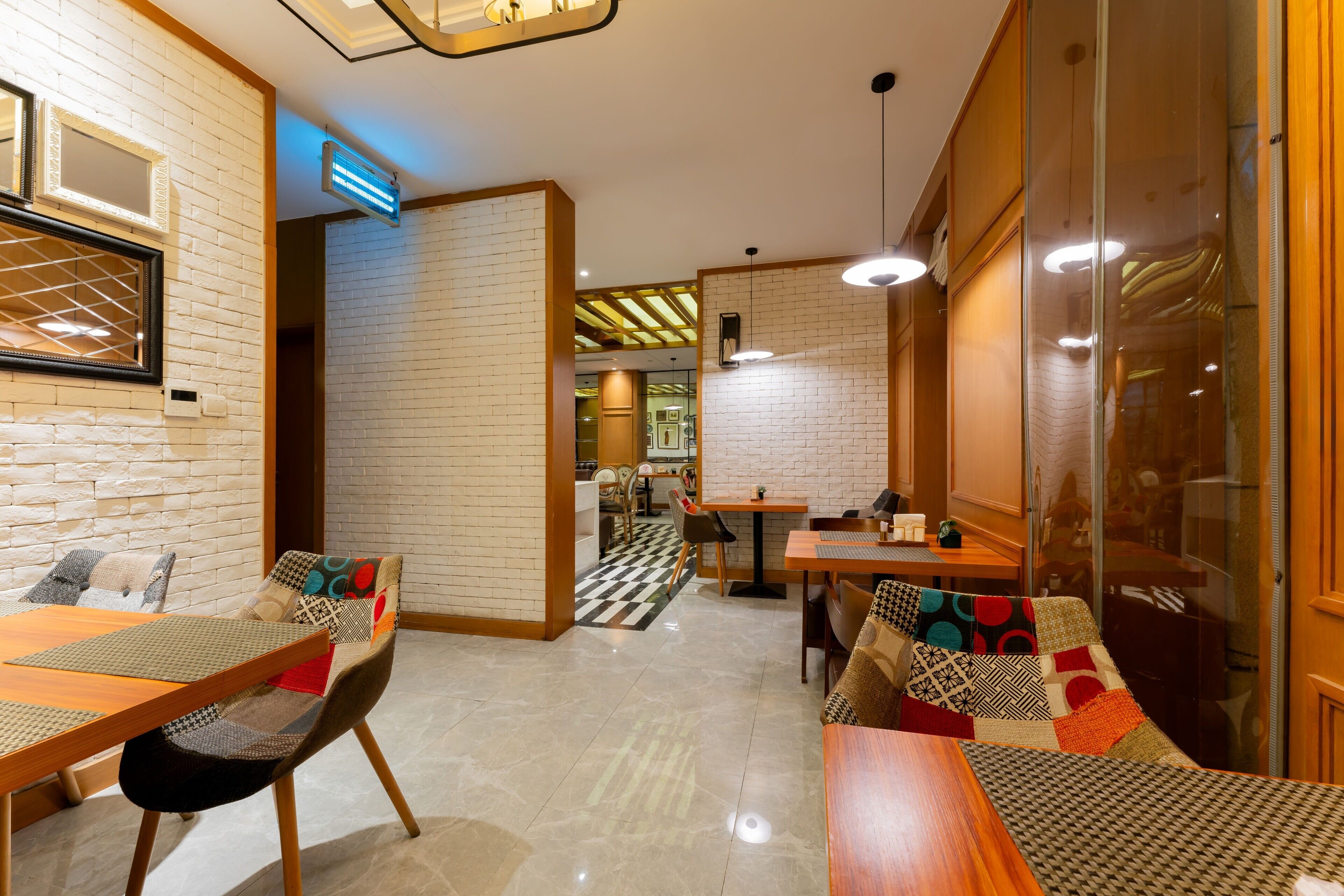 A modern restaurant with brick walls, wooden tables, and patterned cushions.