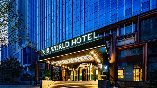 Ein moderner Hotelzugang mit Glasfassade, beleuchteter Beschilderung und einladenden Stufen.