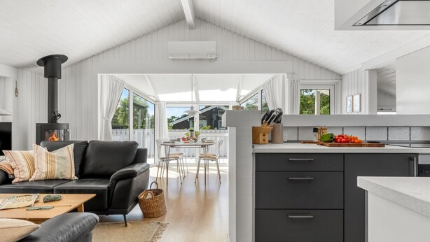 A modern kitchen with a central island, a dining area with a table and chairs, a black leather sofa, and a fireplace. - "Henri" - 1.2km from the sea by Interhome (Hjørring)
