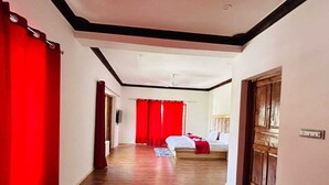 Un couloir d’hôtel avec un plancher en bois, des rideaux rouges et un lit en arrière-plan.