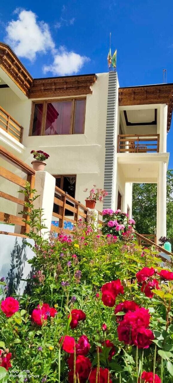 A two-story building with a balcony and a staircase leading to the entrance.