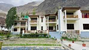 Un immeuble à plusieurs étages doté de balcons, entouré de montagnes.