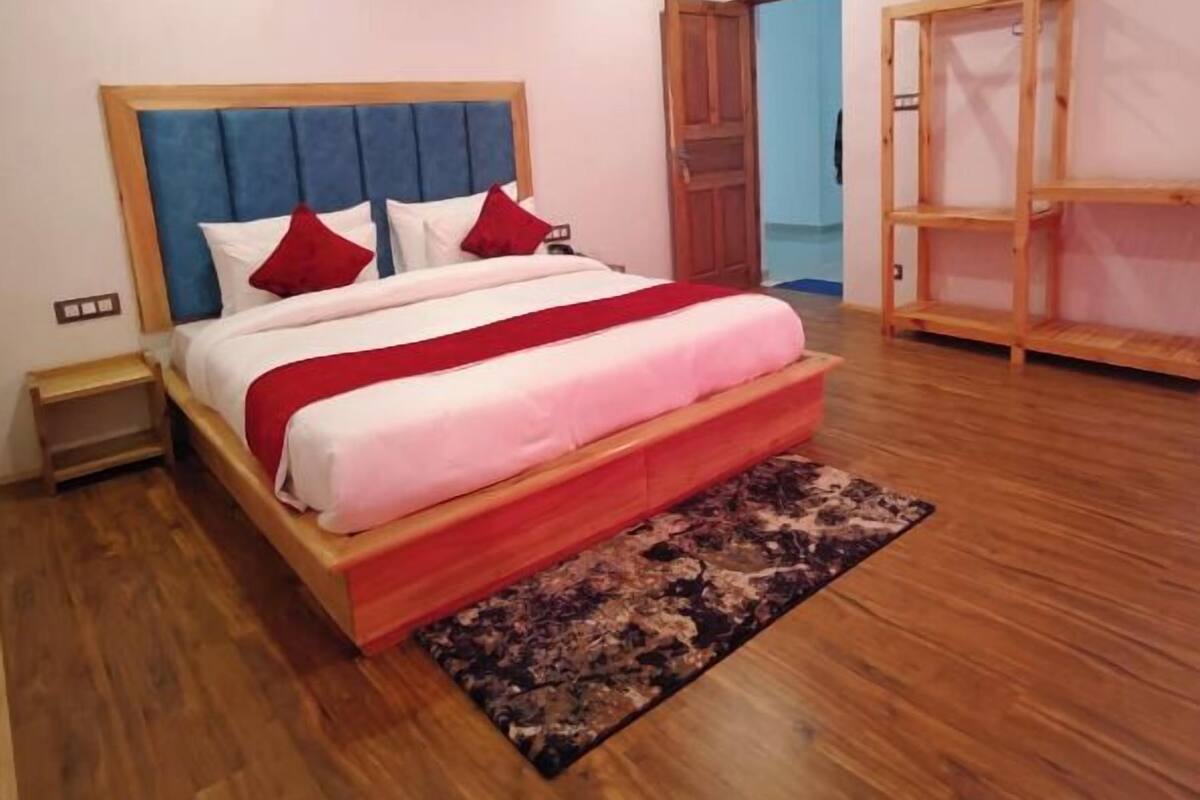 A bedroom with a wooden bed, a ceiling fan, and a view of the outside through an open door.