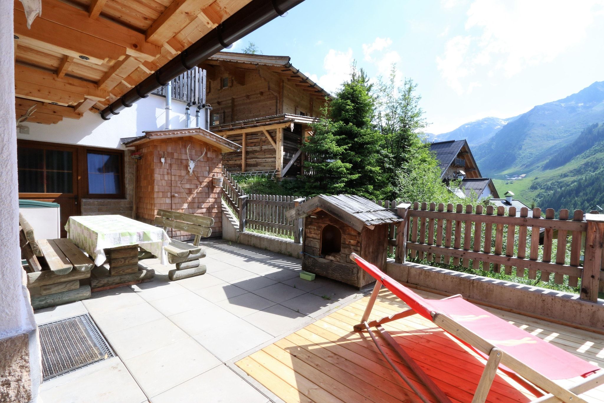 Una terraza de madera con un banco, una pequeña construcción de madera y vistas a un paisaje montañoso.