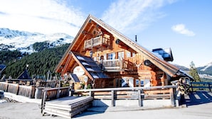 Eine Holzhütte mit Balkon, einer Holzterrasse und einem Berg im Hintergrund.