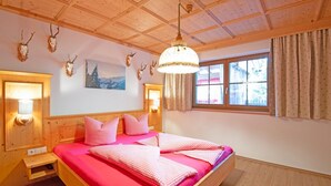 Ein Zimmer in einer Holzhütte mit einem Bett, Holzwänden, einem Gemälde und Dachhirschen.