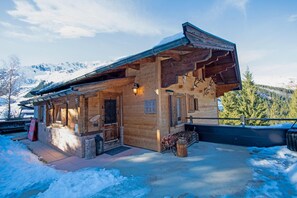 A wooden lodge with a sloped roof, a porch, and a lantern.