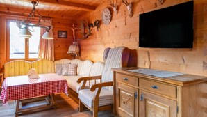 Interior acogedor de una cabaña con techo de madera, una mesa de comedor con mantel a cuadros, un sofá, un mueble de madera y cráneos de animales montados en la pared.