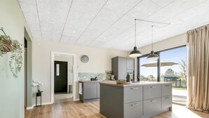 A modern kitchen with a central island, grey cabinets, and a large window providing a view of the outdoors. - "Edvia" - 200m to the fjord by Interhome (Holbæk)