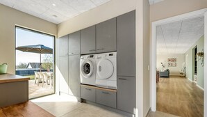 A modern kitchen with grey cabinets, a built-in washing machine, and a wooden dining table. - "Edvia" - 200m to the fjord by Interhome (Holbæk)