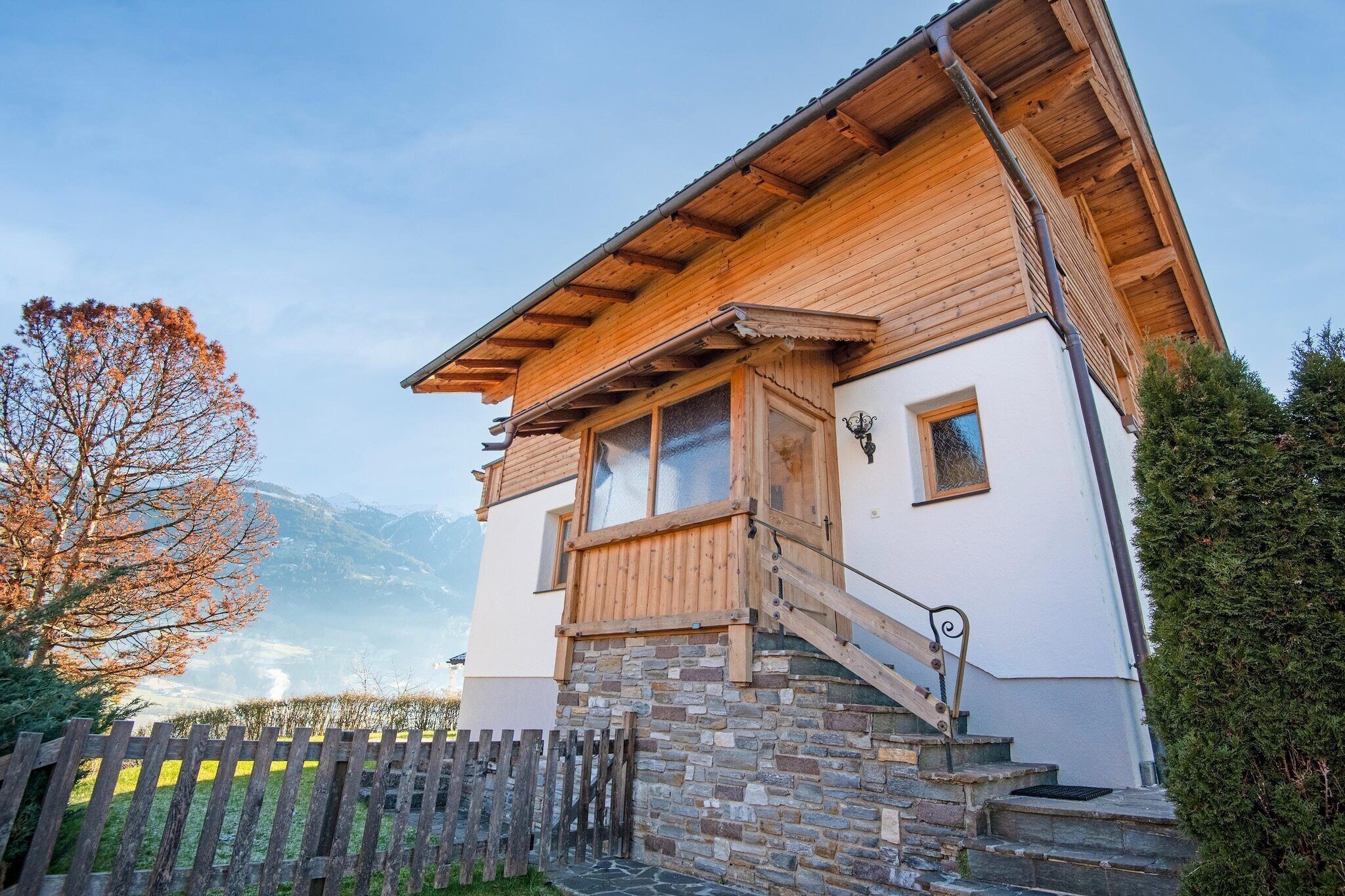 Eine Holzhütte mit Stein Fundament, einer Holztreppe und Blick auf Berge.