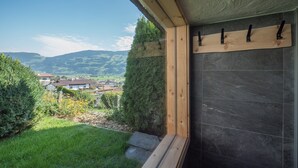 A room with a view of a village and mountains, a wooden shelf with hooks, and a stone wall. - Chalet in Fügen near Spieljoch Ski Lift (Fügen)