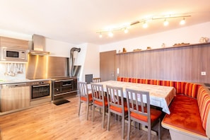 A compact kitchen with modern appliances, a dining area with a bench, and a wooden wall. - Chalet in Mayrhofen near Ski Slopes (Hippach im Zillertal)