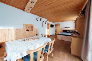 Un interior de madera con una mesa de comedor, sillas, un banco y un televisor.