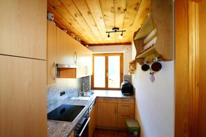 Cocina compacta con armarios de madera, un lavabo, una estufa y una ventana con vistas.