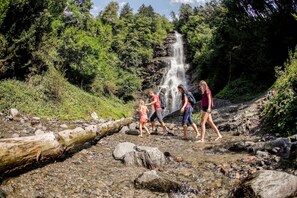 Een natuurlijke omgeving met een waterval, rotsachtig terrein en weelderige begroeiing.