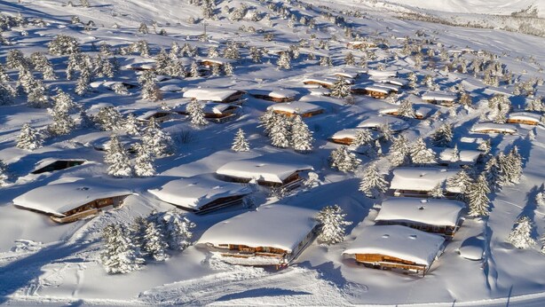 Un paisaje montañoso cubierto de nieve con varias cabañas de madera.