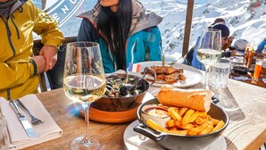 Una mesa de comedor con comida y bebidas, con una vista nevada de montañas al fondo.