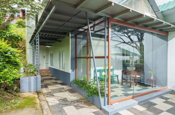 Un edificio moderno con cerramiento de vidrio, asientos al aire libre y suelo a cuadros.