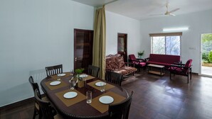 Un comedor con una mesa de madera dispuesta para cuatro personas, un sofá y un ventilador de techo.