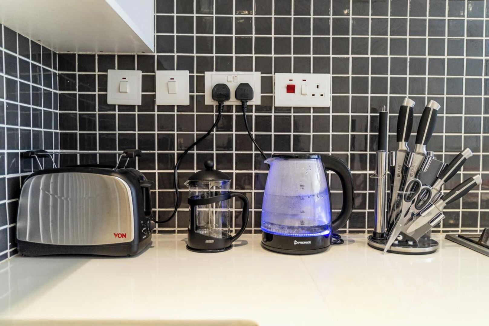 A kitchen with a toaster, a coffee maker, and a knife block on the counter.