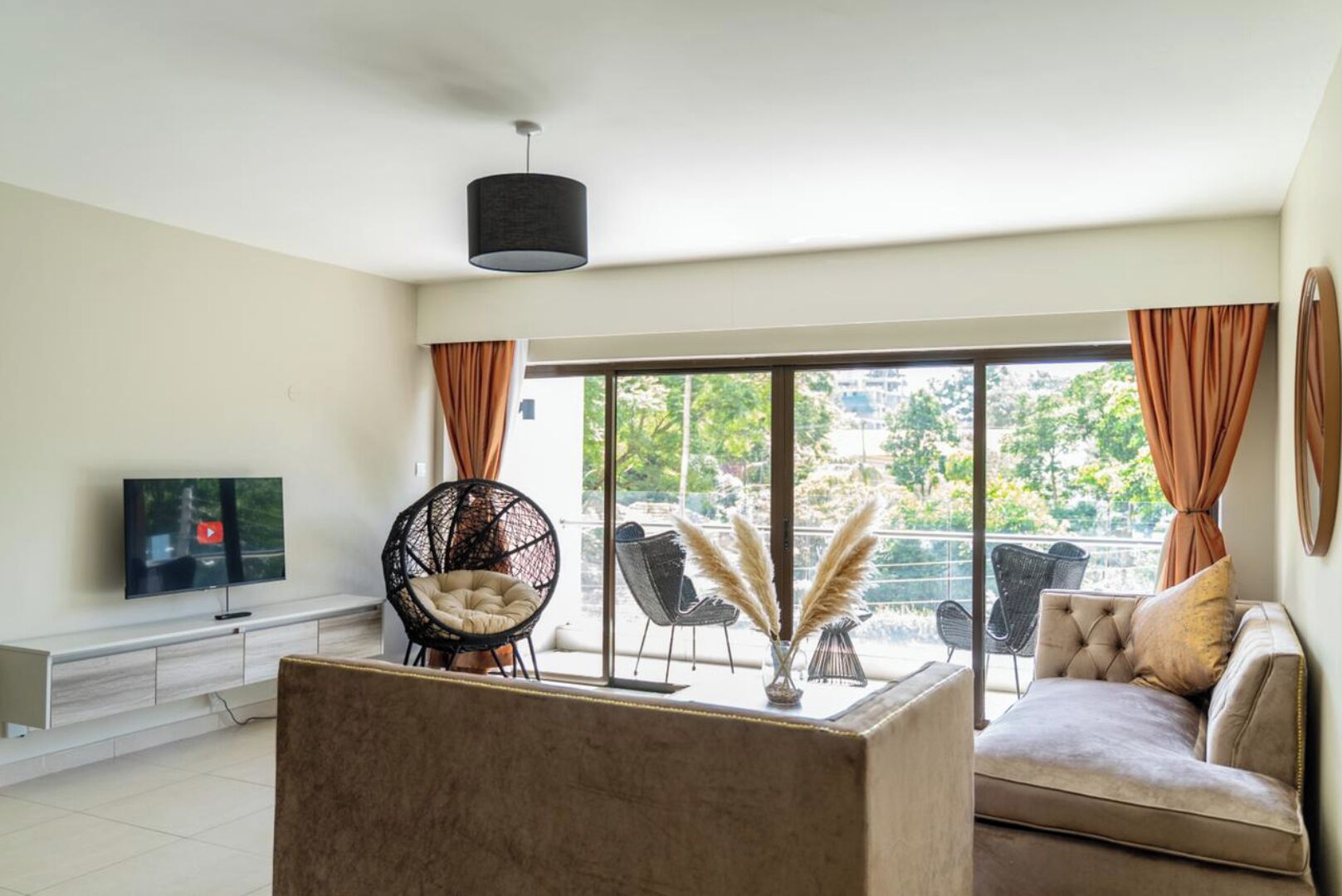 Een moderne woonkamer met een flatscreen televisie, een bank, een salontafel en een balkon met tuinmeubilair.