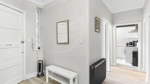 Un couloir avec un banc blanc, un radiateur et un miroir au mur.