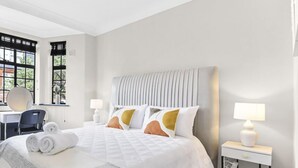 Une chambre d’hôtel moderne, dotée d’un grand lit, d’un bureau et d’une chaise.