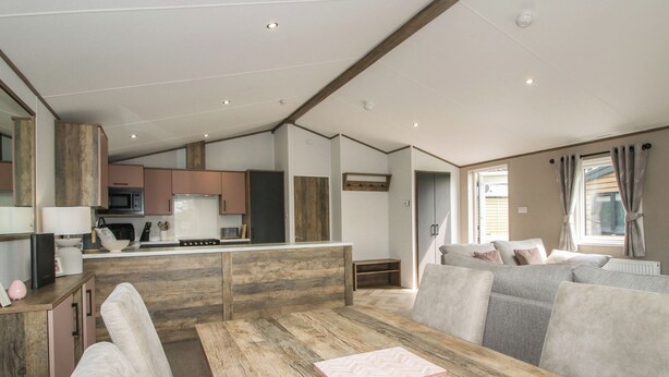 Un interior moderno con una mesa de comedor de madera, un sofá y una zona de cocina.