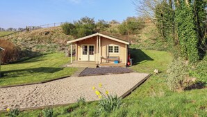 Ein kleines Holzhaus mit Veranda, einem Schotterweg und einer Wiese mit Narzissen.