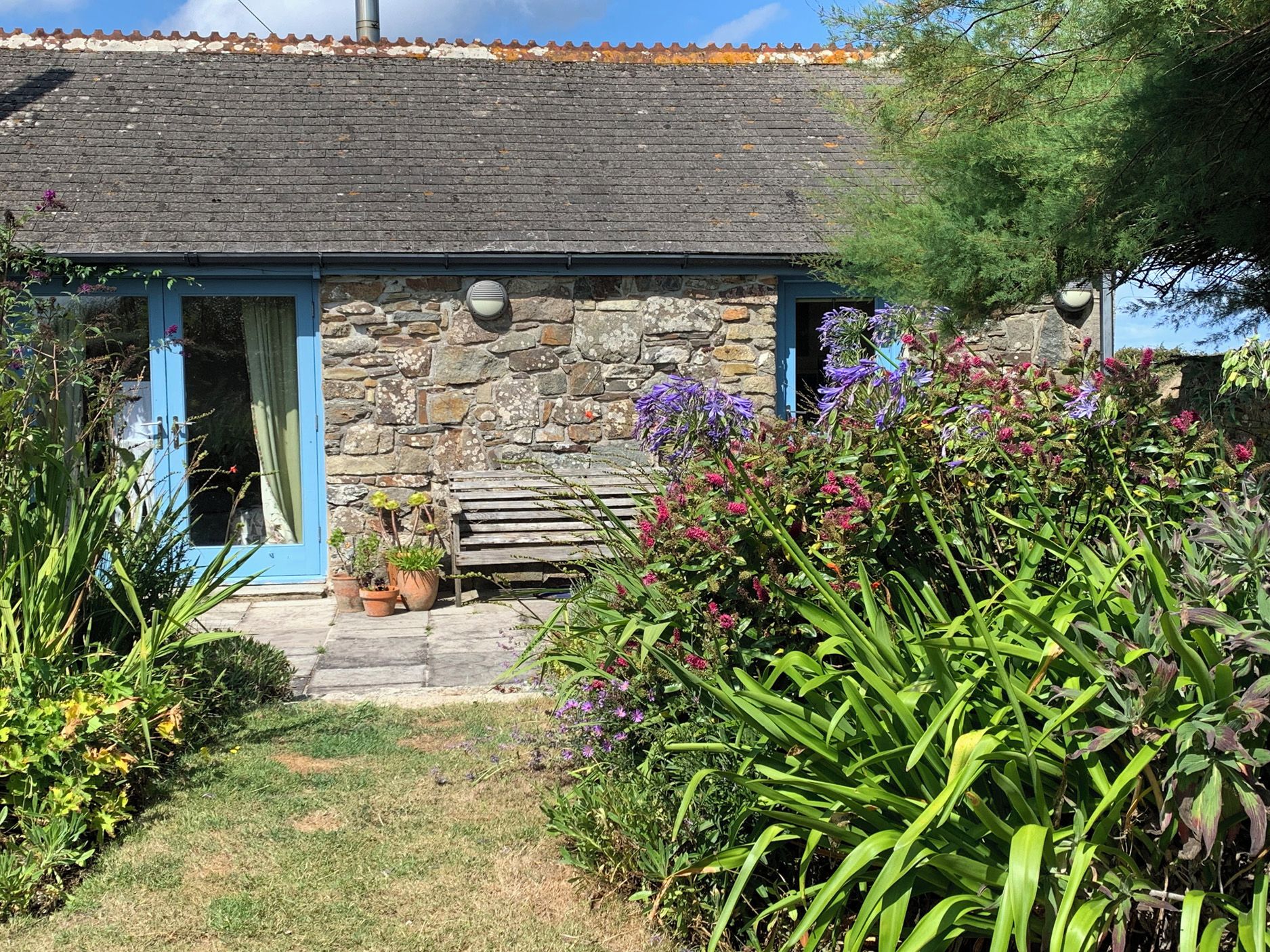 A stone building with a blue door and a small porch area.