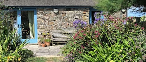 A stone building with a blue door and a small porch area.