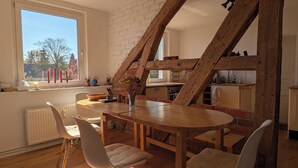 Un coin repas avec une table et des chaises en bois, un mur en briques et une fenêtre décorée de bougies.