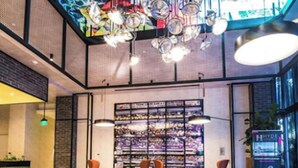 Ein moderner Lounge-Bereich mit einer gebogenen Couch, einem Couchtisch und einer mit Zeitschriften gefüllten Bücherwand.