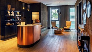 Eine moderne Hotelhalle mit einer zentralen, runden Bar, einer Sitzecke mit Couchtisch und einem Bücherregal.