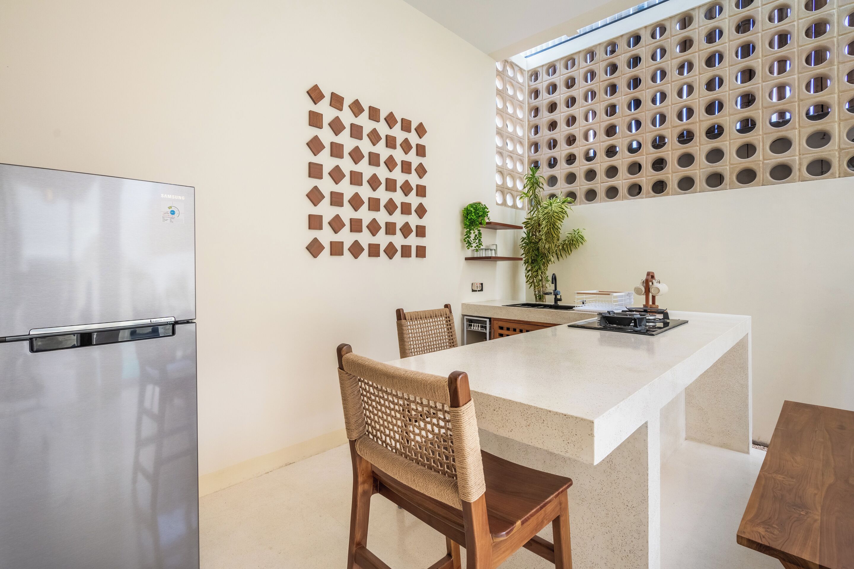 A modern kitchen with a stainless steel refrigerator, a white countertop, and a dining area with wooden chairs.