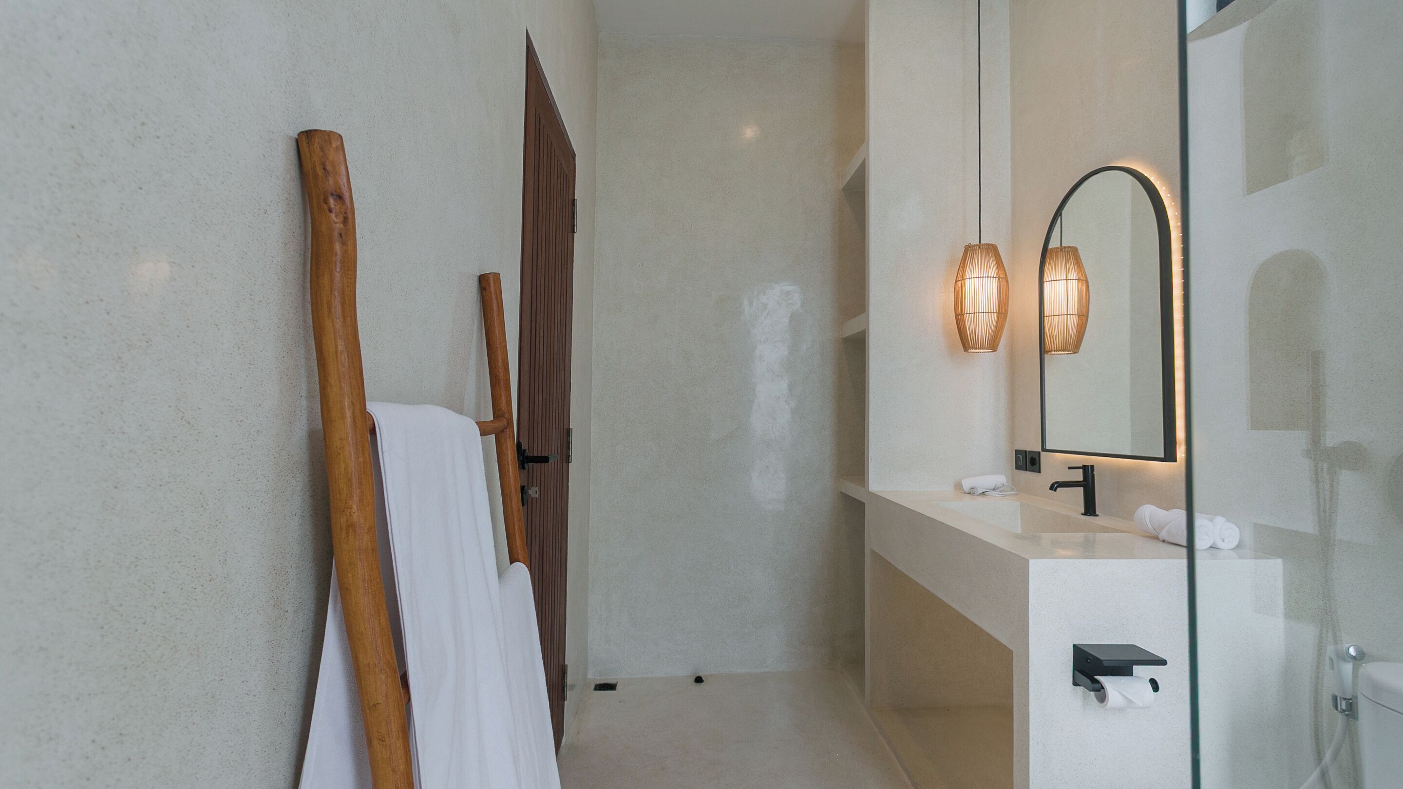 A modern bathroom with a large mirror, a wooden bath mat, a towel, and a glass shower enclosure.