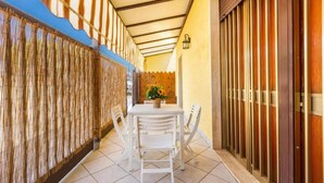 A covered outdoor seating area with a table and chairs, a potted plant, and a wooden fence. - Terrace House by the Sea, Ac, Torre Lapillo (Torre Lapillo)