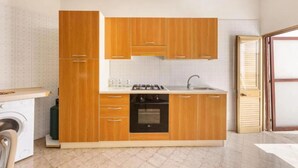 A compact kitchen with wooden cabinets, a built-in oven, and a sink. - Terrace House by the Sea, Ac, Torre Lapillo (Torre Lapillo)