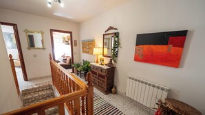 A staircase with wooden railings leading to a landing area with a radiator, a patterned rug, and a wooden cabinet with decorative items. - We have ski slopes. The hike up to La Covatilla takes 5 minutes. (San Bartolomé de Béjar)