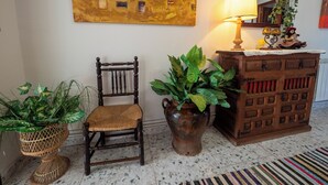 A room with a wooden chair, a potted plant, a wooden cabinet with a mirror, and a painting on the wall. - We have ski slopes. The hike up to La Covatilla takes 5 minutes. (San Bartolomé de Béjar)