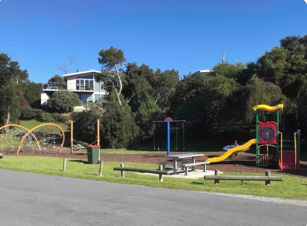 Une aire de jeux avec des balançoires, un toboggan et des structures d’escalade.