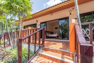 Un hotel con una escalera de madera que conduce a un área exterior cubierta, una cama visible en el interior y el número '16' en la pared.